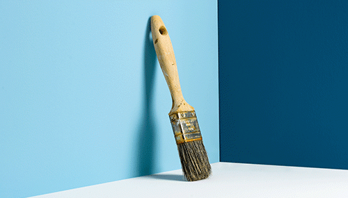 Pinsel vor zweifarbiger Wand symbolisiert Veränderung und Anpassung im Change Management